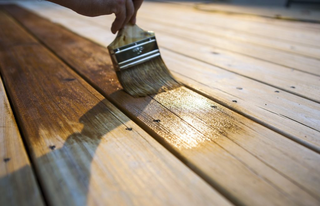 male carpenter applying varnish to wooden furniture.